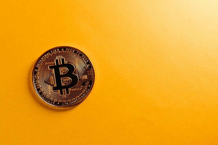 Bitcoin coin placed on a bright yellow background offering ample copy space.