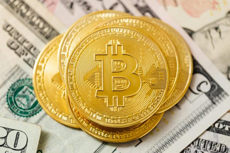 Detailed view of golden Bitcoin coins atop US dollar bills, symbolizing cryptocurrency investment.