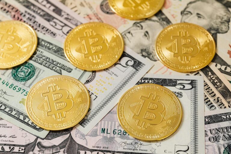 Golden Bitcoin coins scattered over US dollar bills, symbolizing modern digital currency.