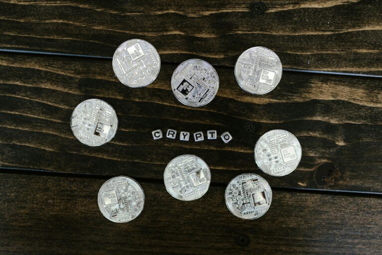 Silver cryptocurrency coins arranged on a wooden surface spelling 'crypto'.